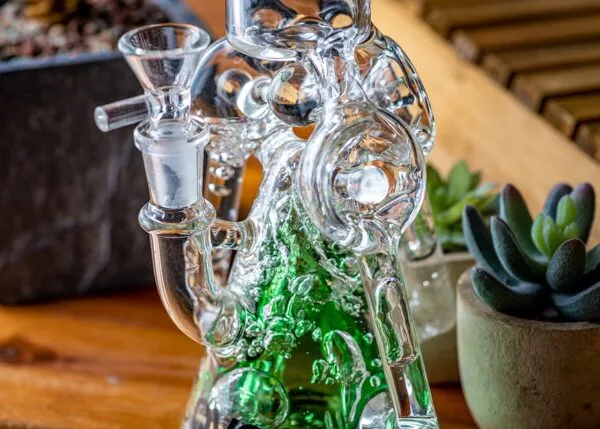 Clear glass water pipe with green bubbling liquid, intricate percolator, and bowl piece.
