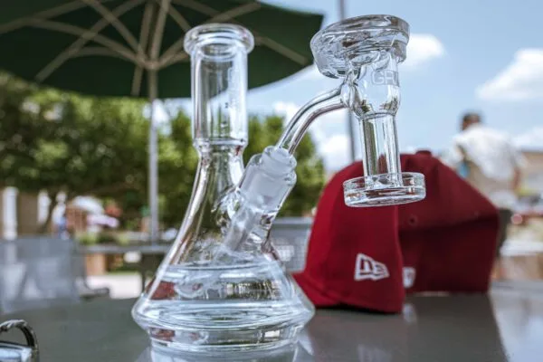 Clear glass beaker water pipe with dab banger on an outdoor table.