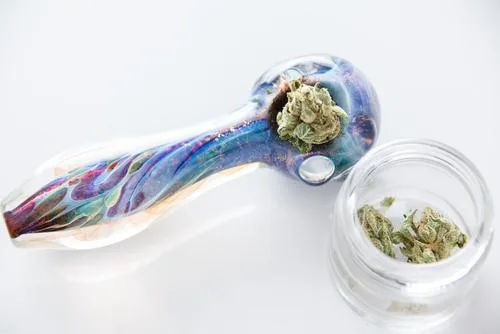 Vibrant glass pipe with cannabis bud and a jar of marijuana flower.