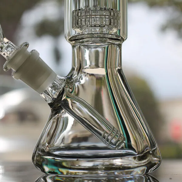 Close-up of clear glass beaker bong with percolator and downstem for filtration.