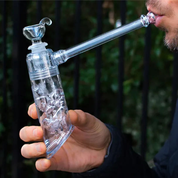 A man holds and inhales from a portable clear glass water pipe bubbler.