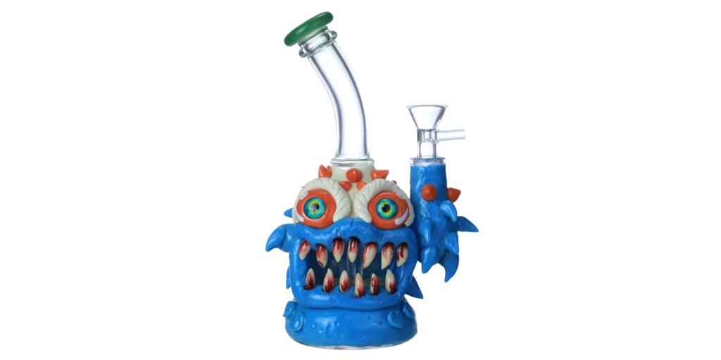 Blue monster glass bong with bloodshot eyes, sharp fangs, and green mouthpiece.