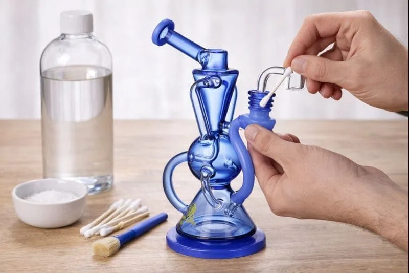 Person cleaning blue glass dab rig banger with cotton swab and supplies.
