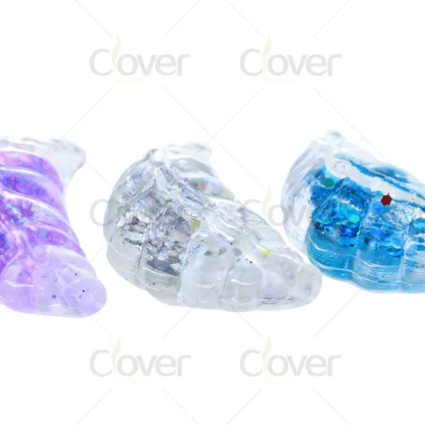Three sparkling glass shells filled with purple, clear, and blue glitter.