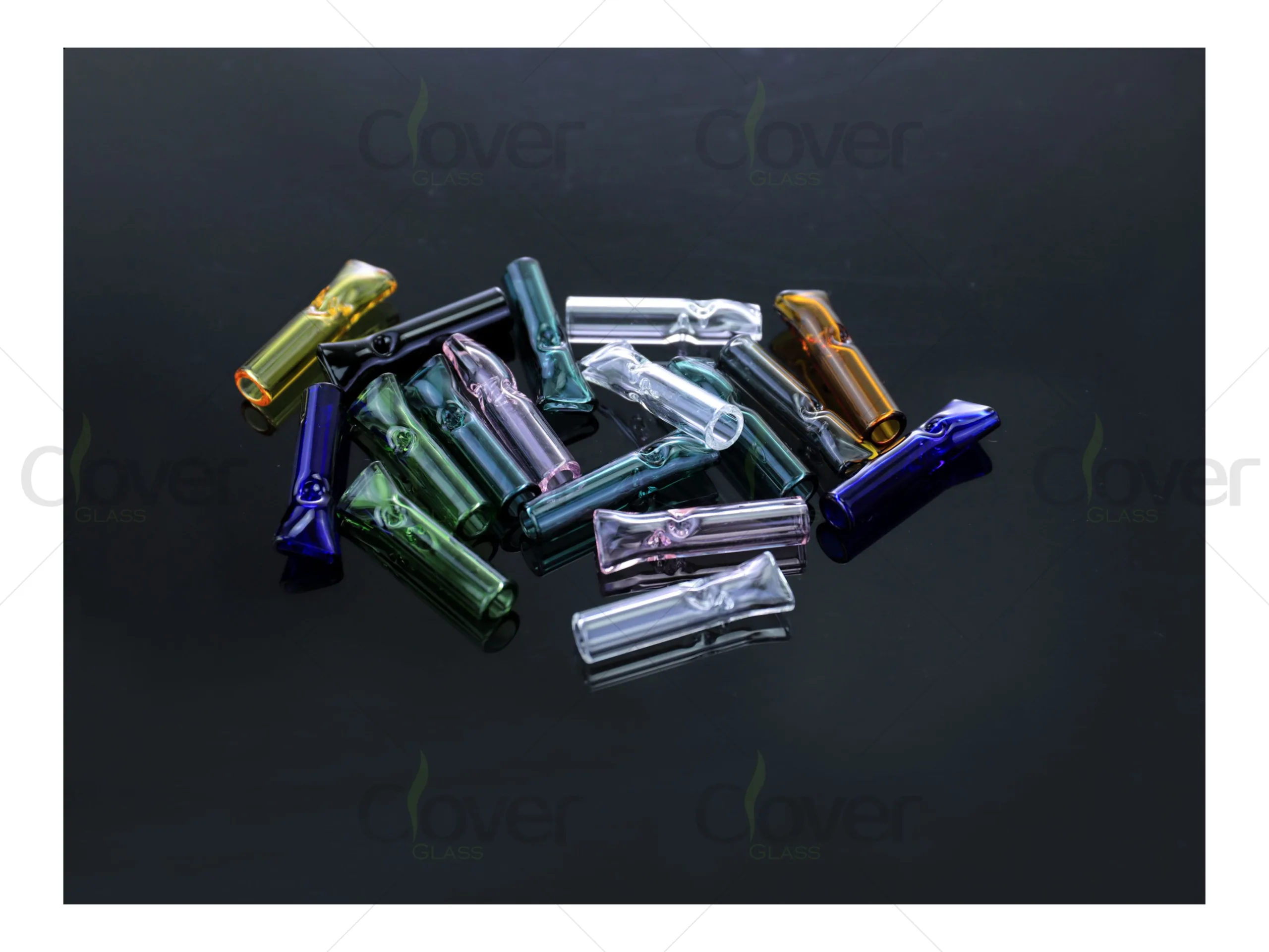 Assorted colorful borosilicate glass filter tips scattered on a dark reflective surface.