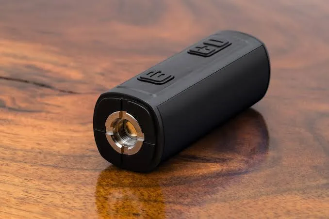 Compact black vape battery mod with 510 thread connector on wood.